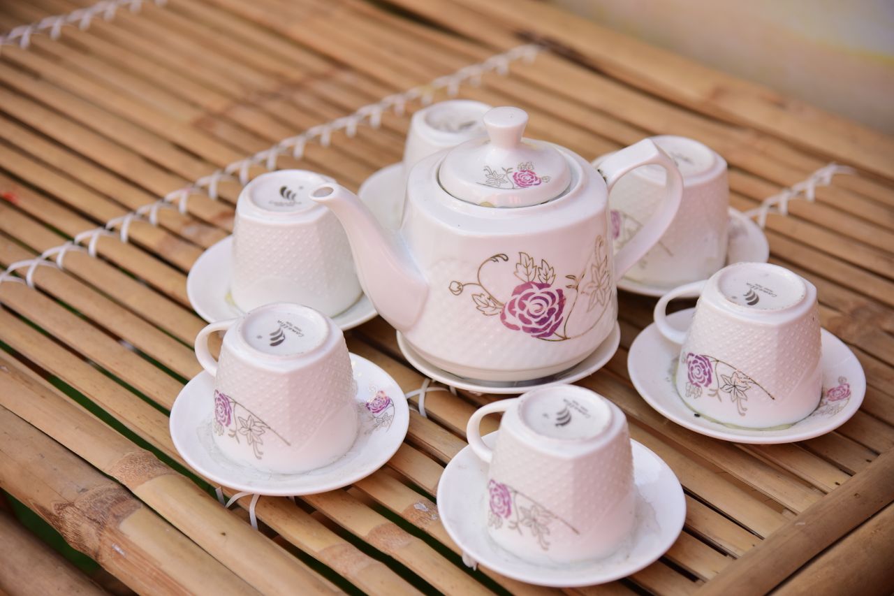 a beautifully designed floral tea set displayed on a bamboo table perf
