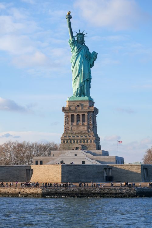 Free Iconic Statue of Liberty under blue skies, showcasing freedom in New York City. Stock Photo