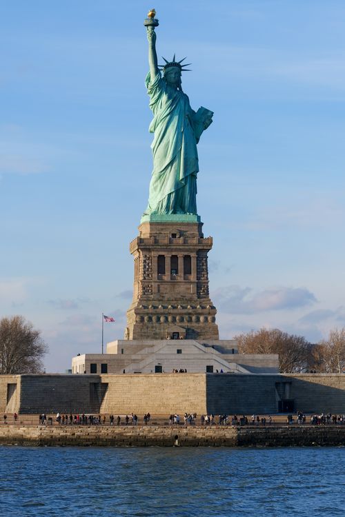 Free View of the Statue of Liberty on Liberty Island against a clear sky in New York City. Stock Photo