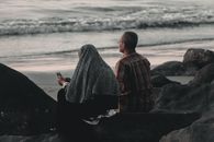 一对老年夫妇坐在海边的岩石上，享受着宁静的时刻