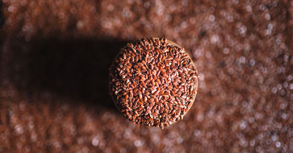 A top-down view of a jar filled with flax seeds, surrounded by scattered seeds on the surface. - Evidence evidence guide for black seed oil gut health meta-analysis