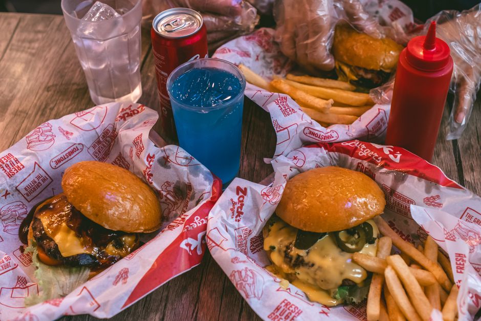 Mouth-watering cheeseburgers with fries and refreshing drinks served in a casual restaurant setting.