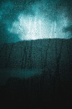 Close-up of rain droplets on a window capturing a moody and dramatic ambiance.