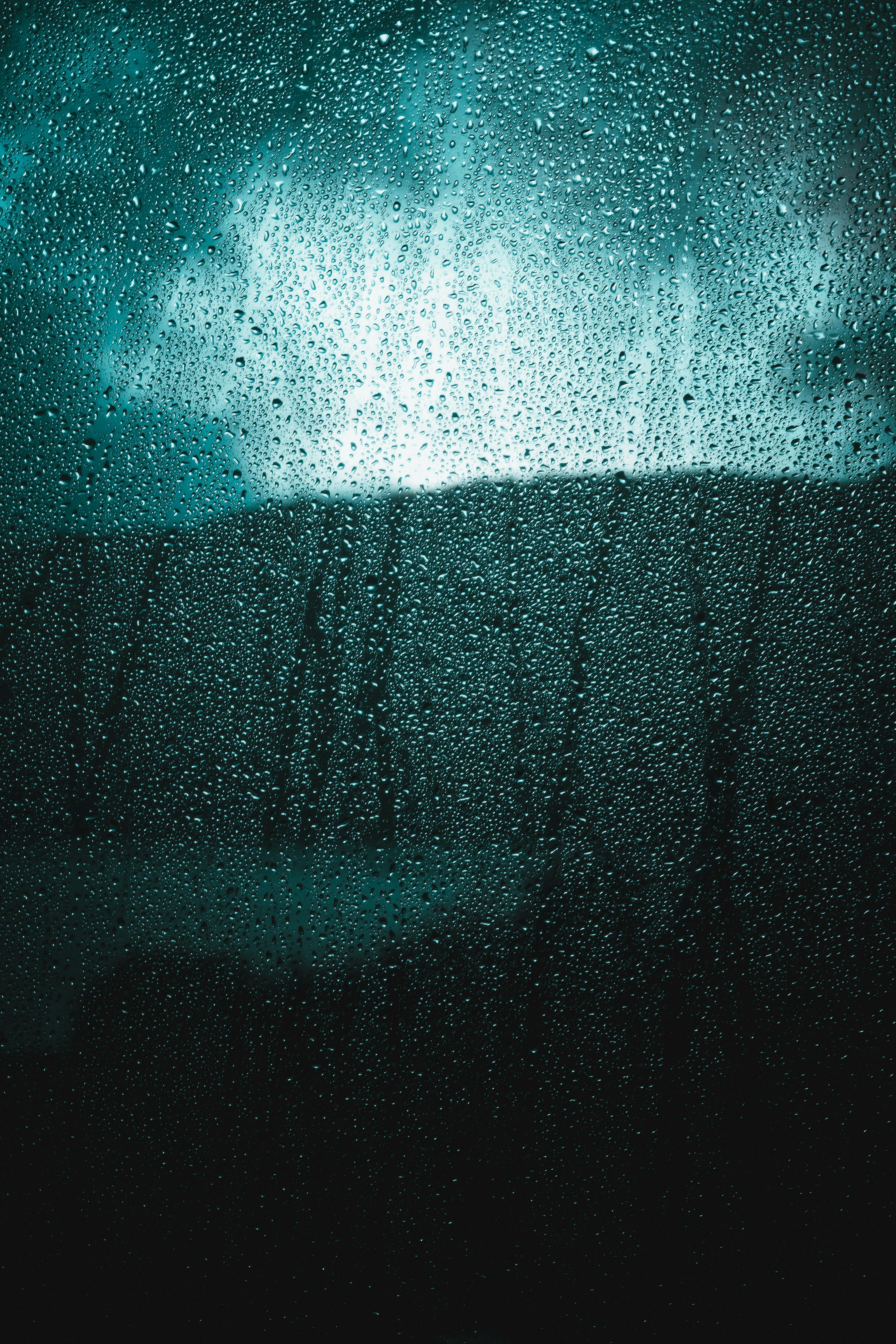 Gratis Tampilan jarak dekat tetesan hujan di jendela yang menangkap suasana muram dan dramatis. Foto Stok