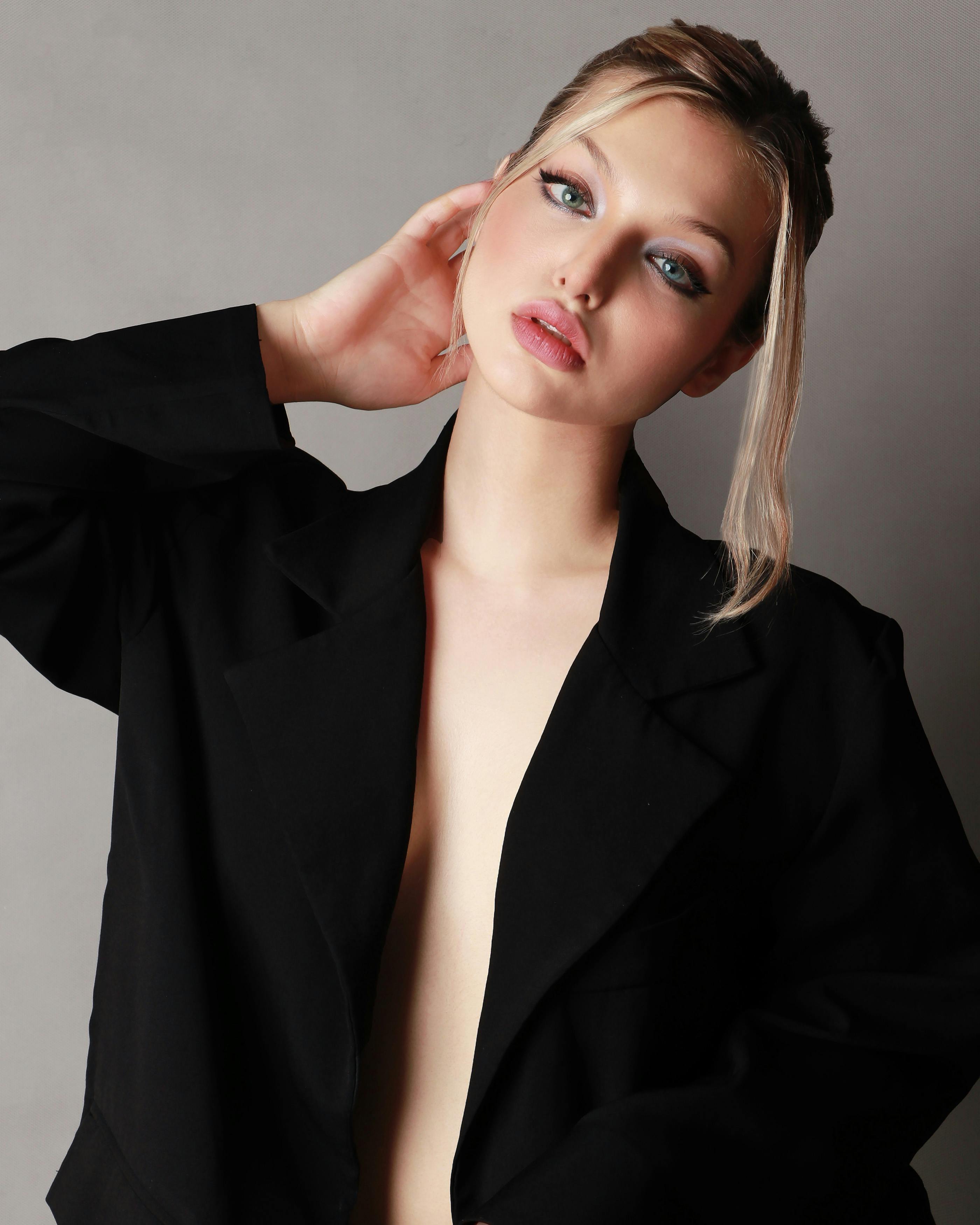 Gratis Ritratto sofisticato di una giovane donna con un elegante cappotto nero, che trasuda eleganza e compostezza. Foto a disposizione