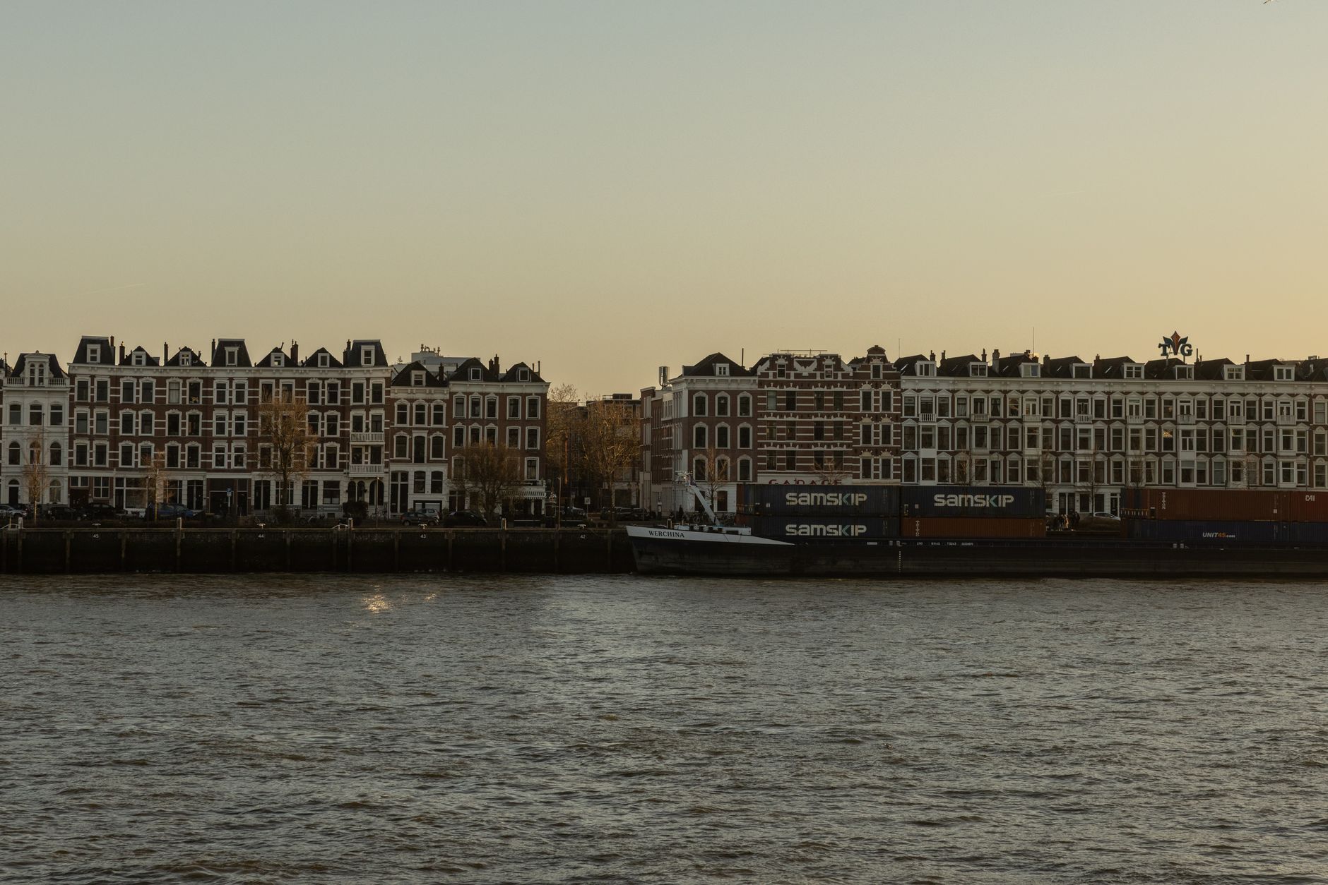 Een elegante rij gebouwen langs de haven van Rotterdam, vastgelegd tijdens een serene zonsondergang.