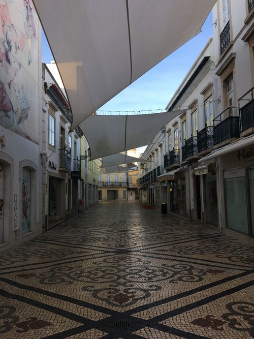 Free Empty cobbled street with awnings in Faro, Portugal illuminated by daylight. Stock Photo