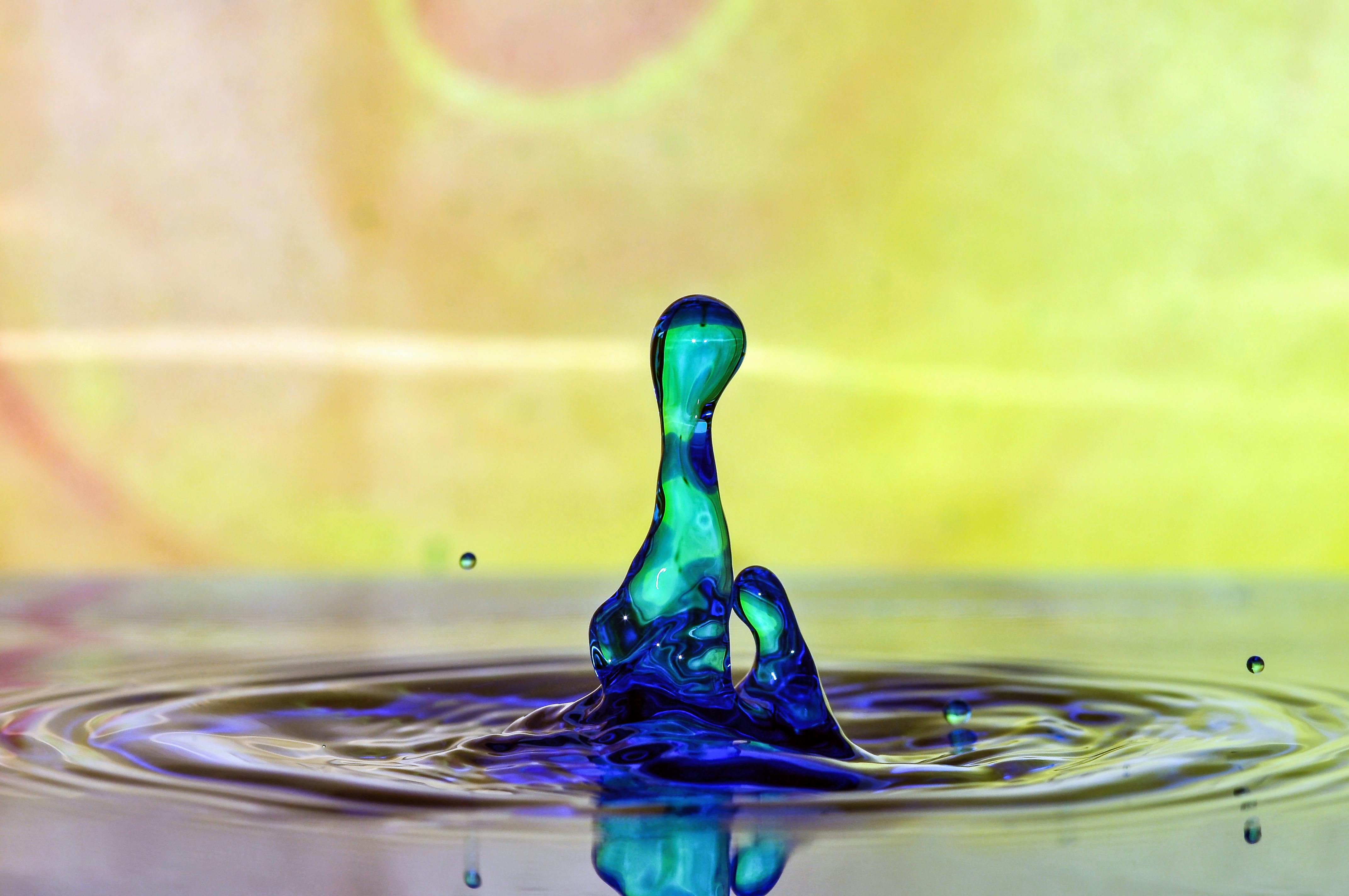 Miễn phí Ảnh cận cảnh trừu tượng về một giọt nước màu xanh lam rực rỡ bắn tung tóe trên nền vàng. Ảnh lưu trữ
