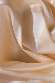 Close-up of beige satin fabric texture with soft folds and elegant shine.