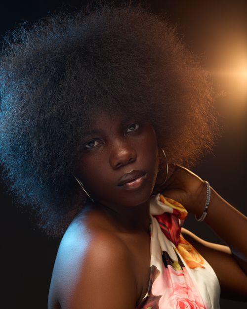 Free A captivating portrait of a young woman with a voluminous afro, wearing floral attire. Stock Photo