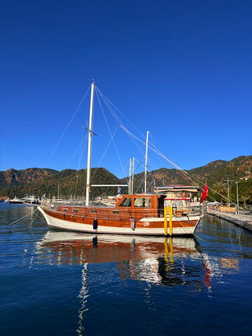 Free A classic wooden boat docked in a tranquil marina under a clear blue sky. Stock Photo