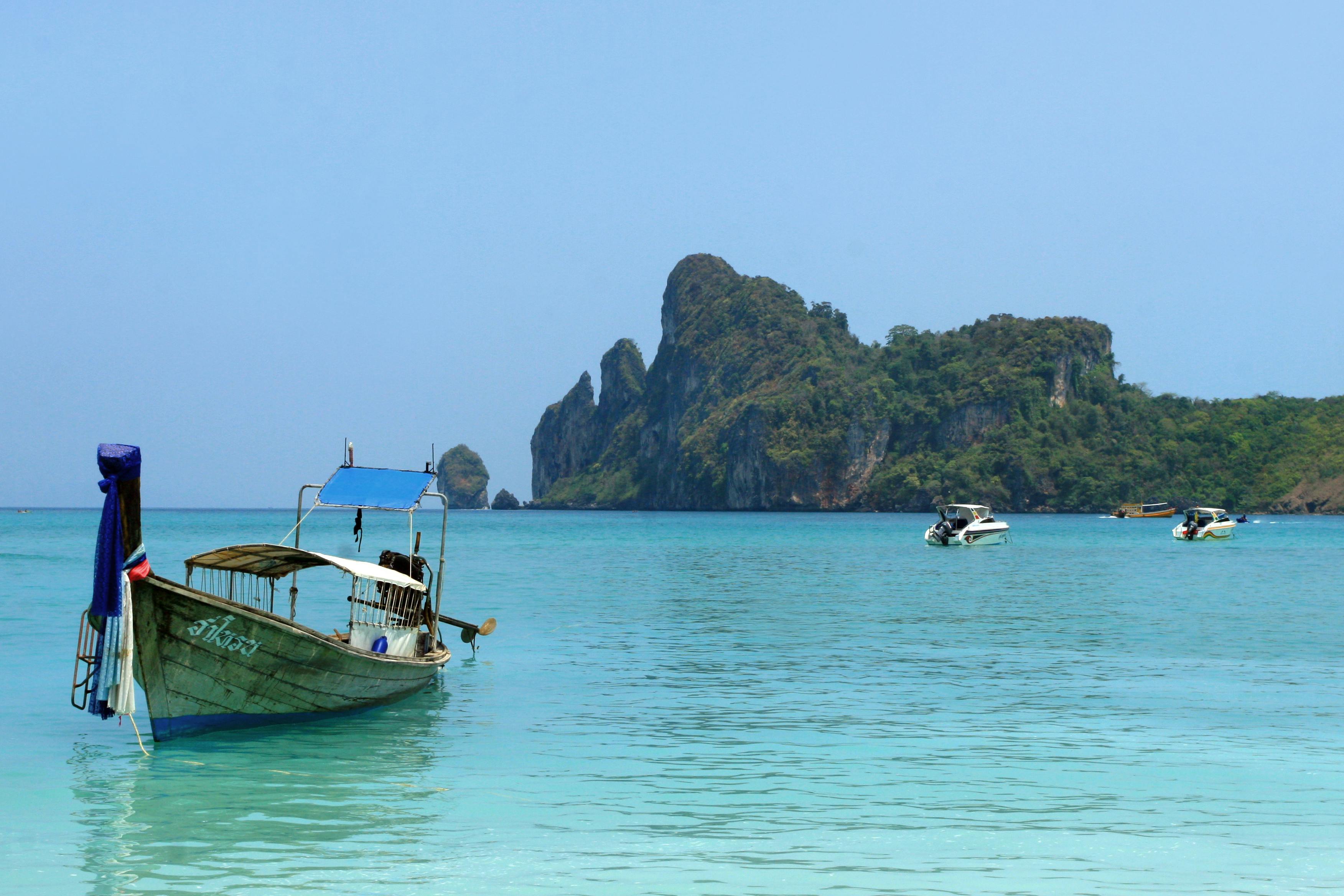 Longtail boat floating in turquoise waters near a Thai island on a sunny day.