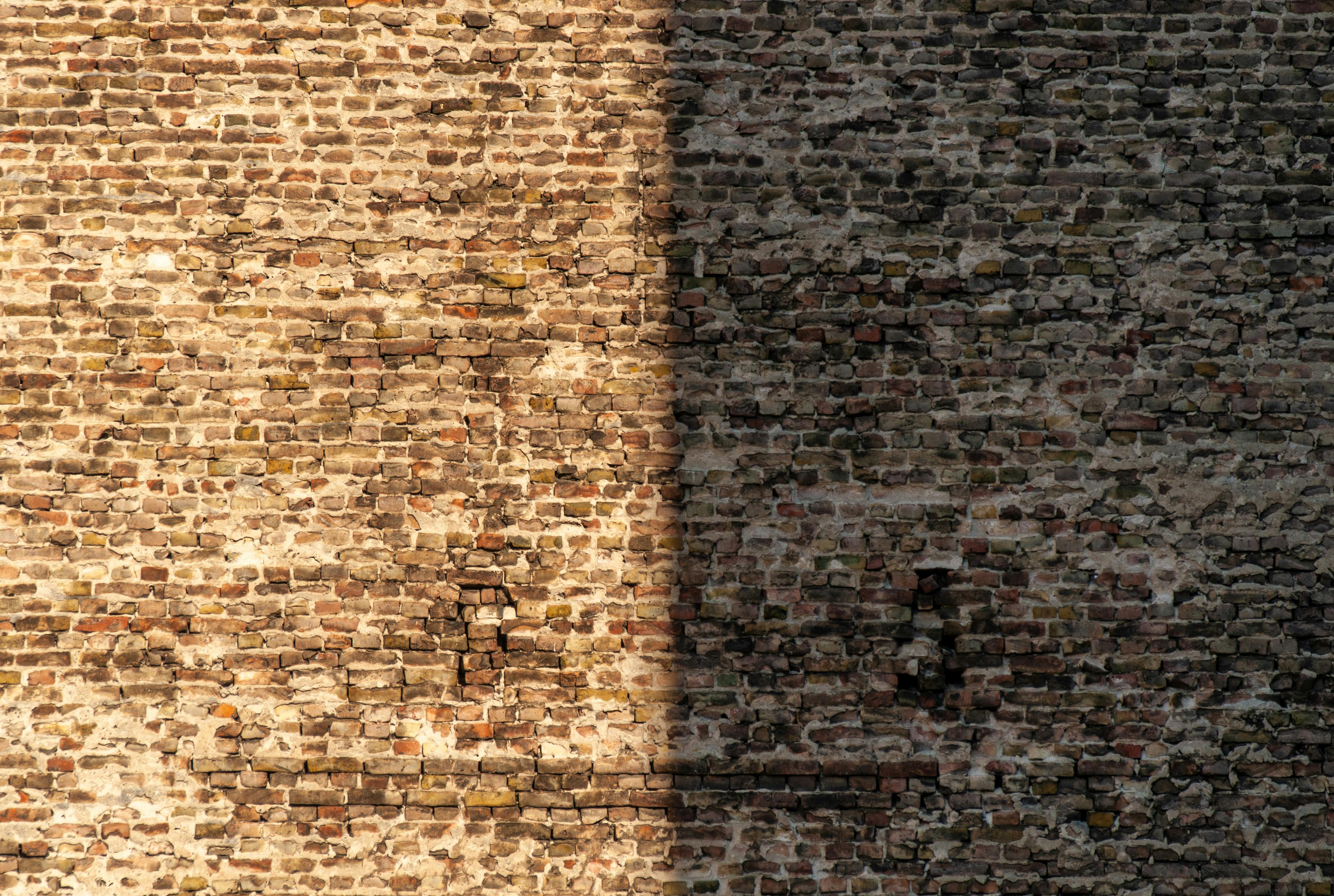 Gratis Un muro di mattoni che mette in risalto il forte contrasto tra luci e ombre, evidenziandone la consistenza. Foto a disposizione