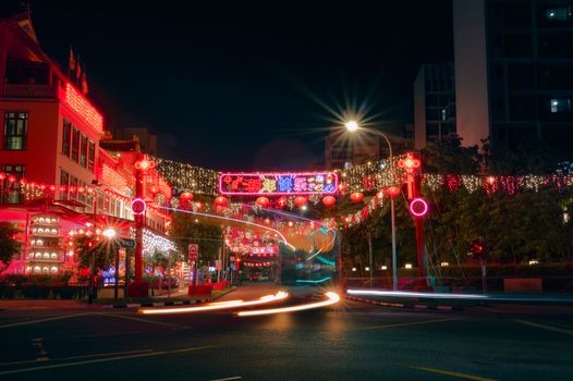 Nighttime street with vibrant lanterns and neon lights during a festival, exuding a lively atmosphere.