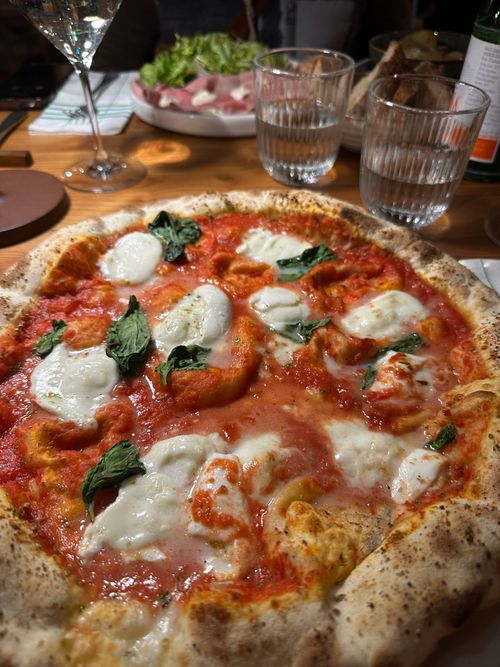 Free Close-up of a freshly baked Margherita pizza with mozzarella and basil on a wooden table. Stock Photo