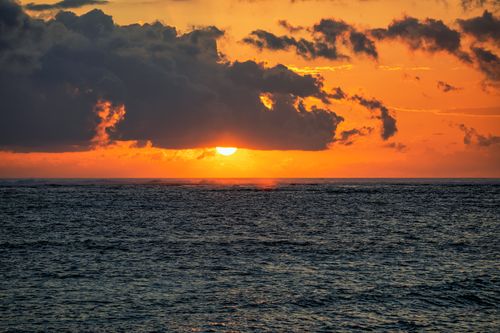 Free A breathtaking sunset over the ocean in Bali with vivid colors and dramatic clouds. Stock Photo