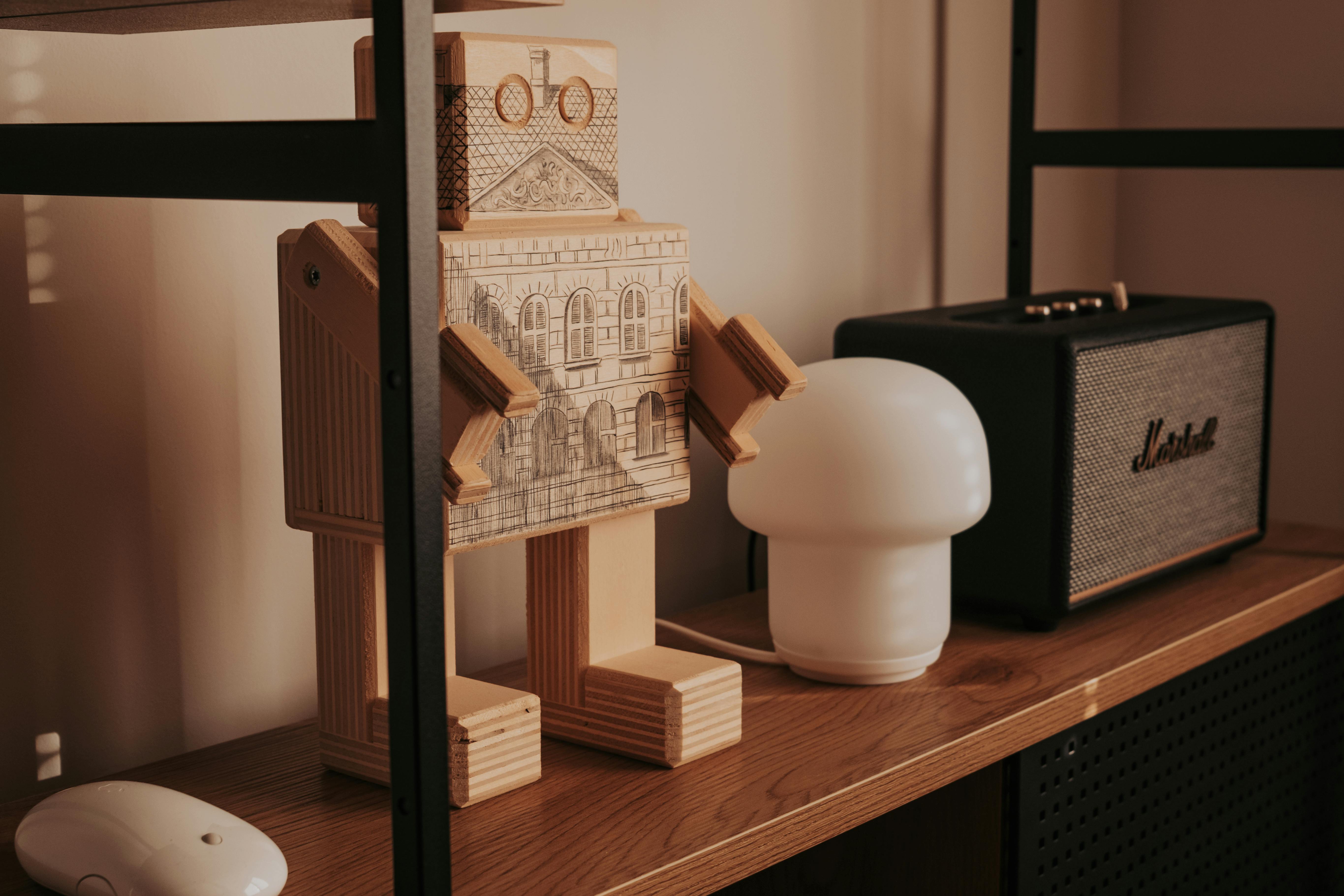 Δωρεάν Κομψή διάταξη με ξύλινο ρομπότ, μοντέρνα λάμπα και ρετρό ηχείο σε ξύλινο ράφι. Φωτογραφία από στοκ φωτογραφιών