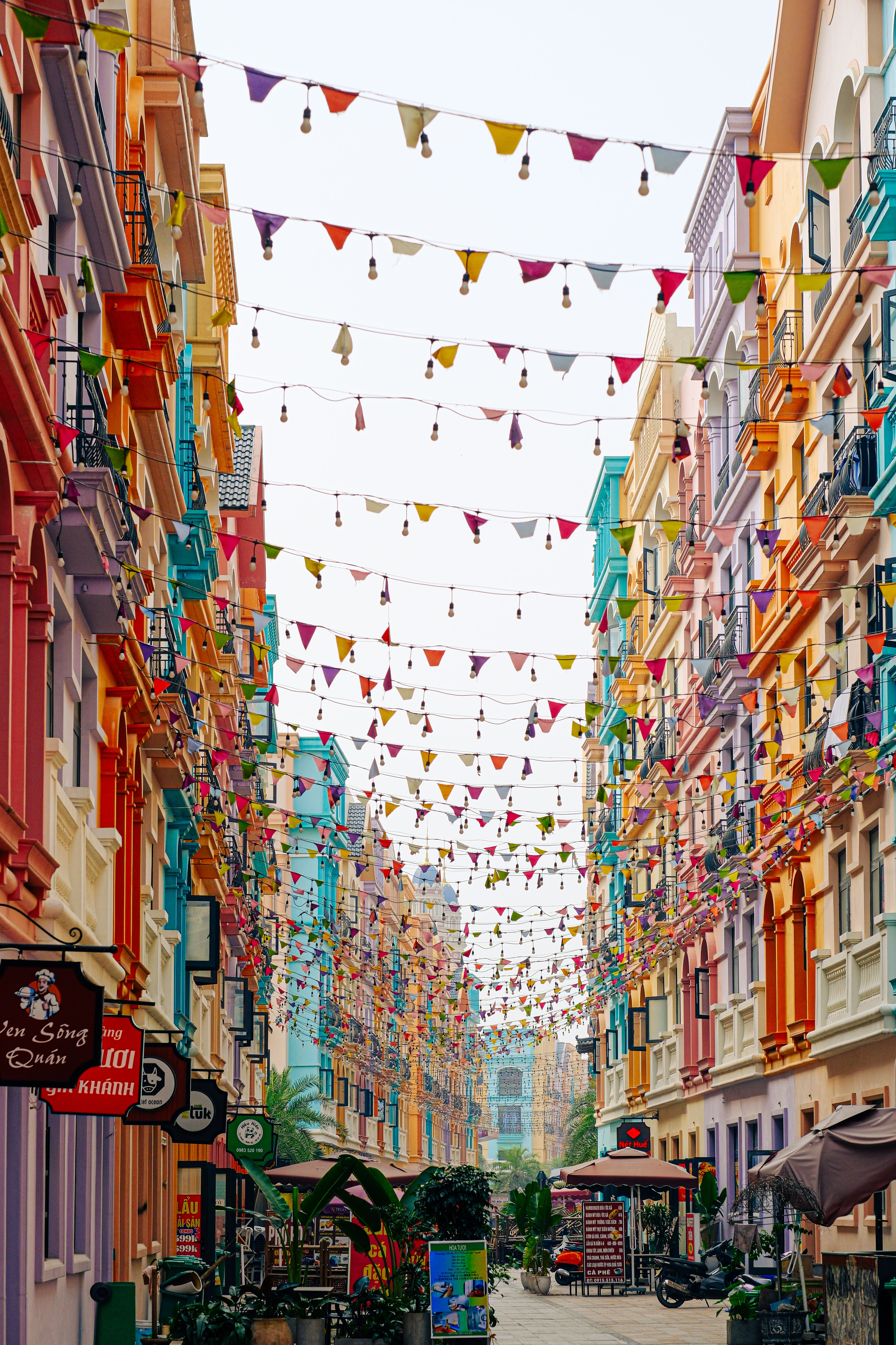 grátis Rua colorida da cidade com fachadas de prédios vibrantes e decorações de bandeirolas, perfeita para temas de estilo de vida urbano. Foto profissional