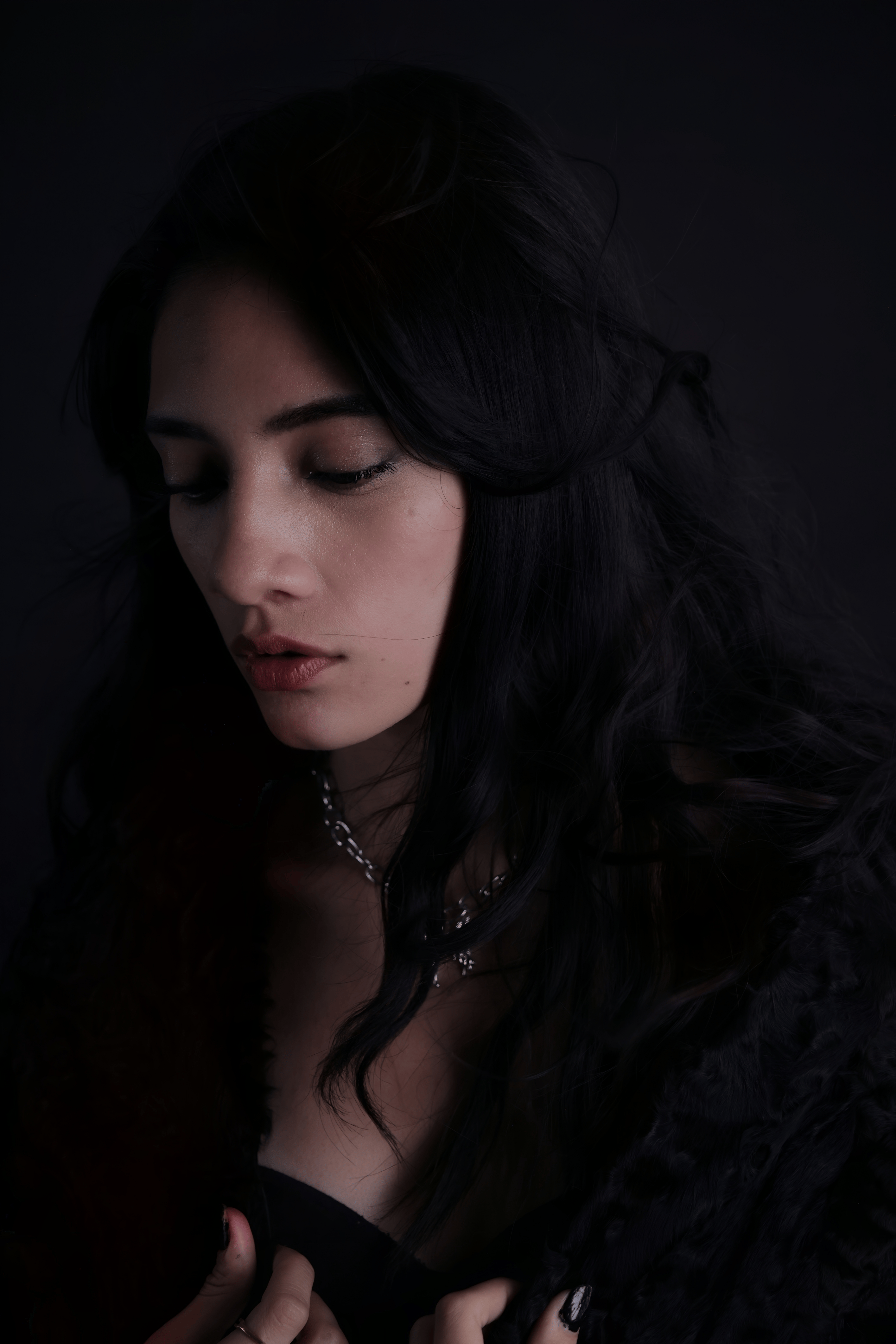 Gratis Una donna pensierosa in una luce scura crea un'atmosfera intima e suggestiva. Foto a disposizione