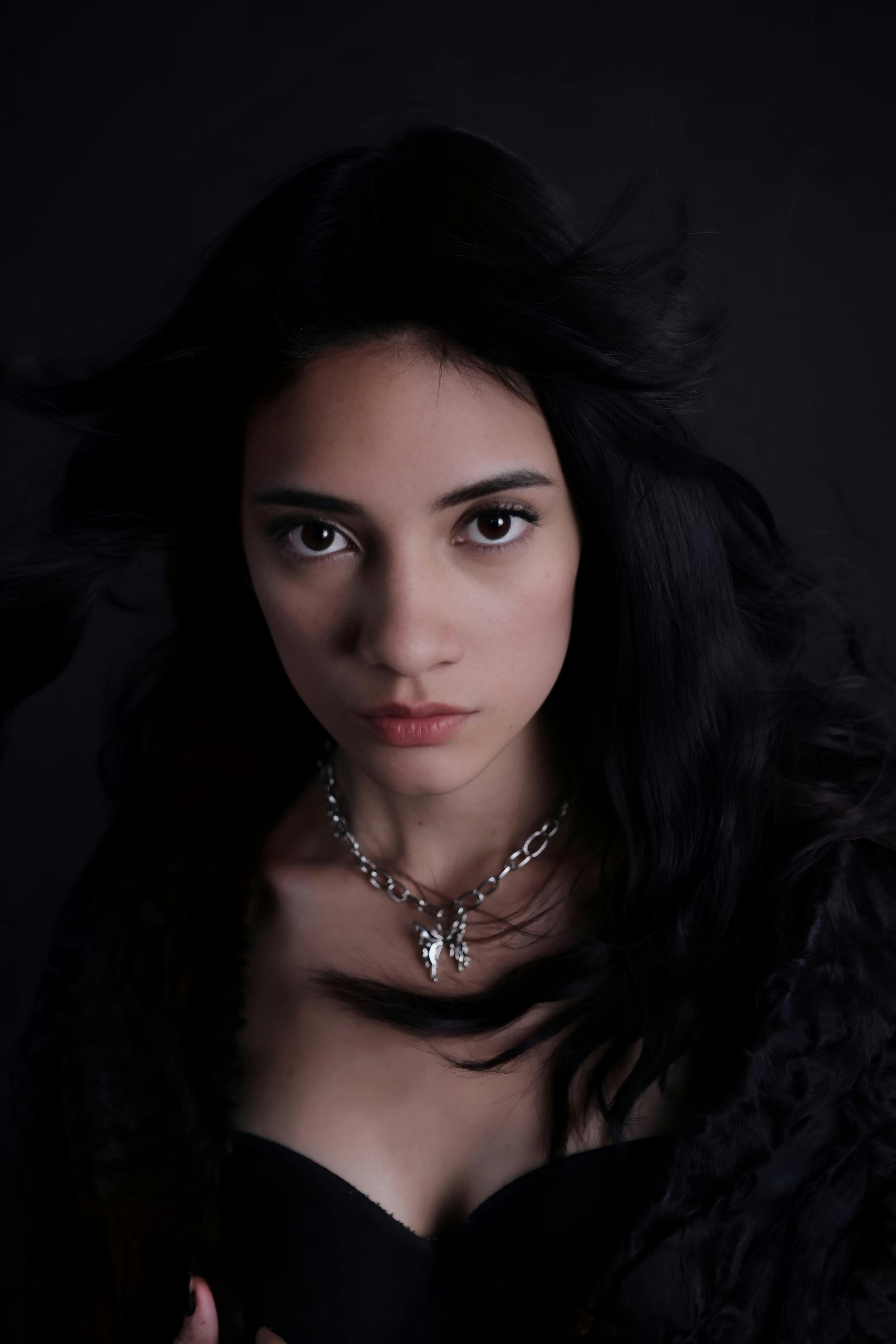 grátis Retrato marcante de uma mulher de cabelos escuros contra um fundo melancólico. Foto profissional