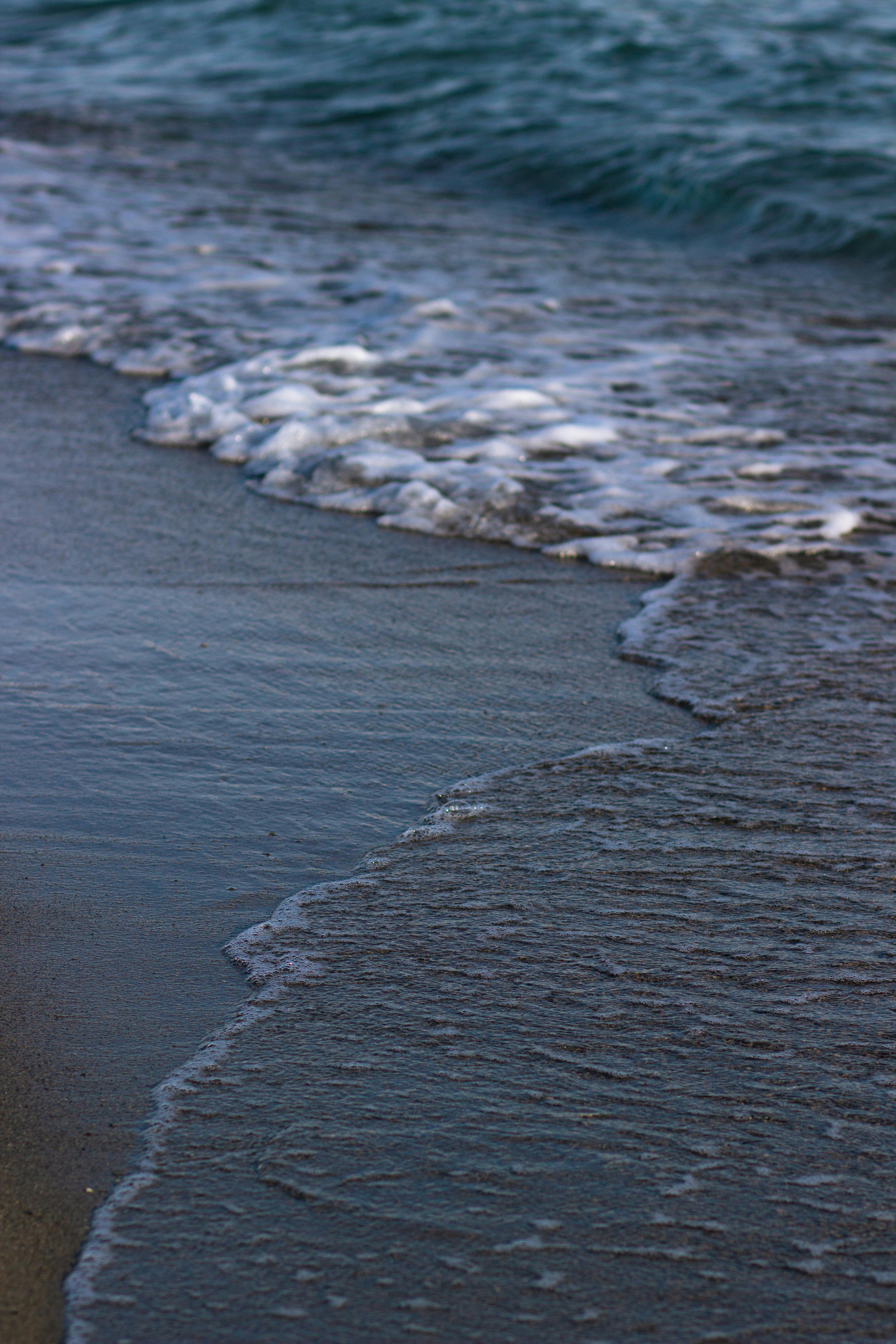 grátis Ondas suaves banham as margens do lago Issyk-Kul, capturando um momento sereno no Quirguistão. Foto profissional