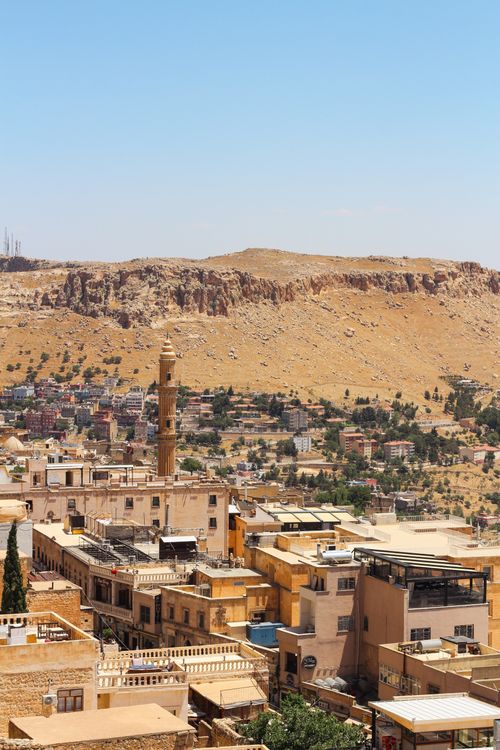 Free A beautiful panoramic view of Mardin, Turkey, showcasing historic architecture and a prominent minaret under a clear blue sky. Stock Photo