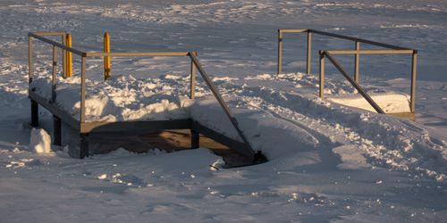 Free Snow-covered pier on a frozen lake during winter, showcasing a serene cold landscape. Stock Photo