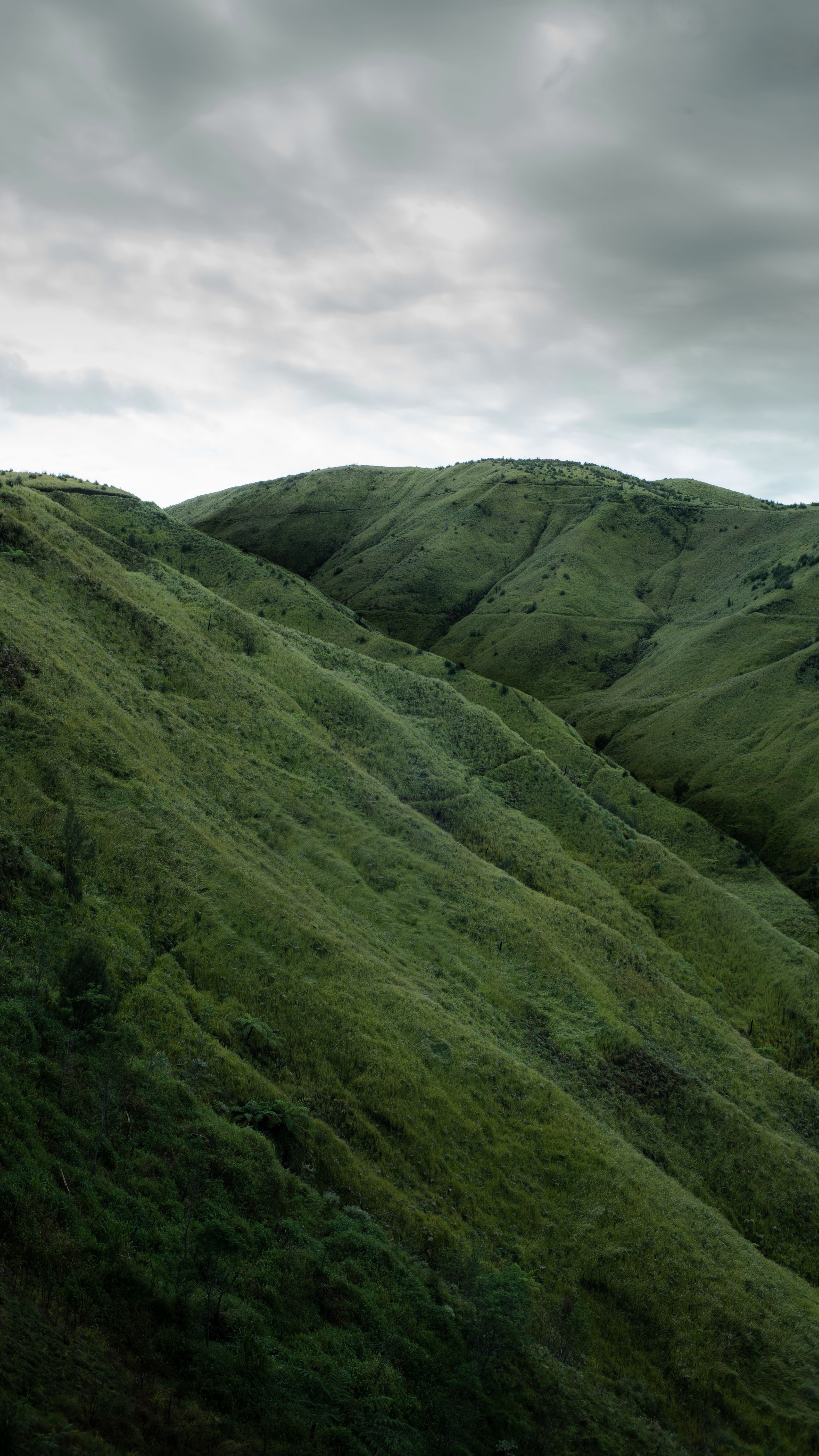 Lush Green Hills Under Cloudy Sky · Free Stock Photo
