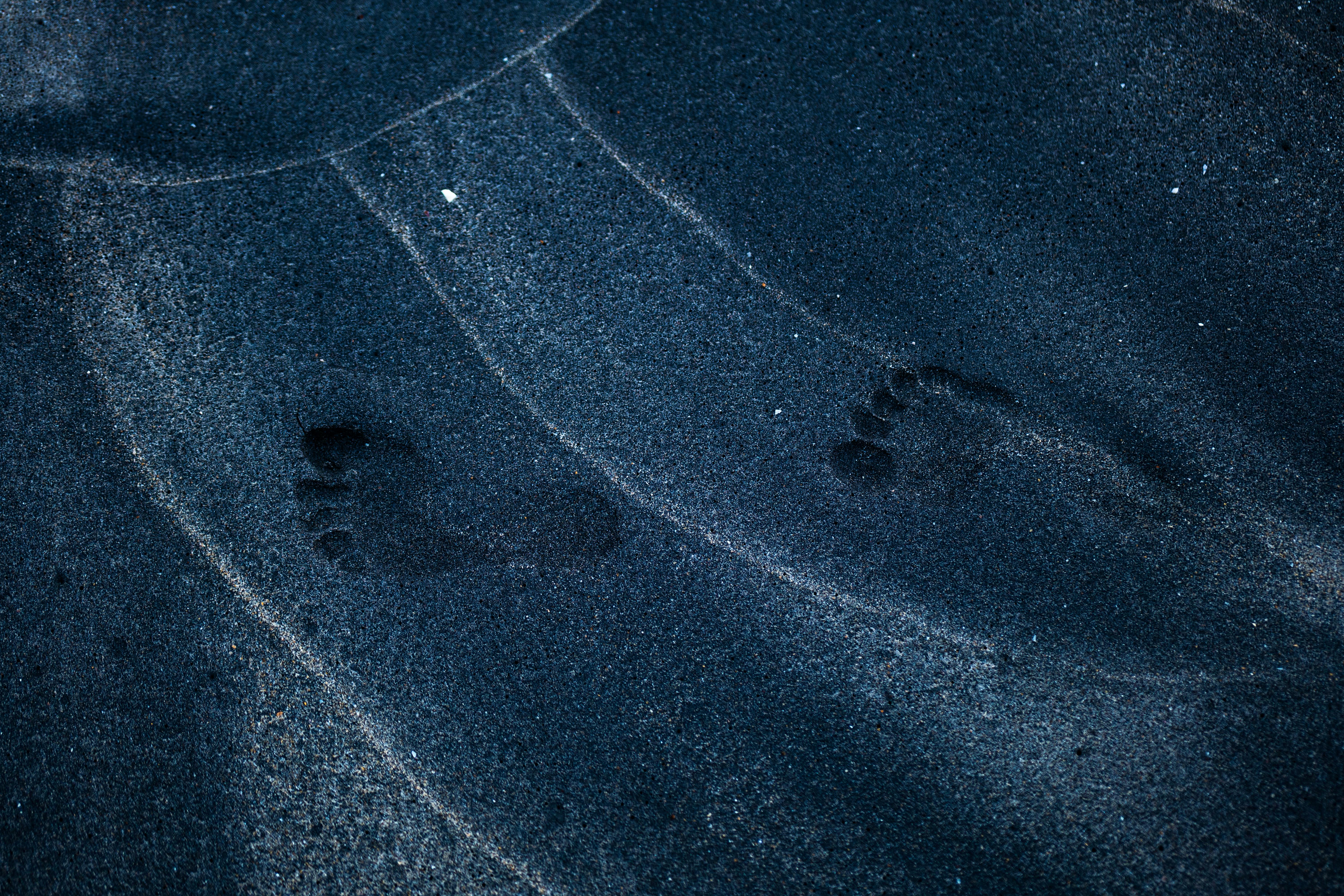 Δωρεάν Μυστηριώδη ίχνη σε μια σκοτεινή, ανάγλυφη μαύρη αμμουδιά, που προκαλούν μια αίσθηση μοναξιάς. Φωτογραφία από στοκ φωτογραφιών