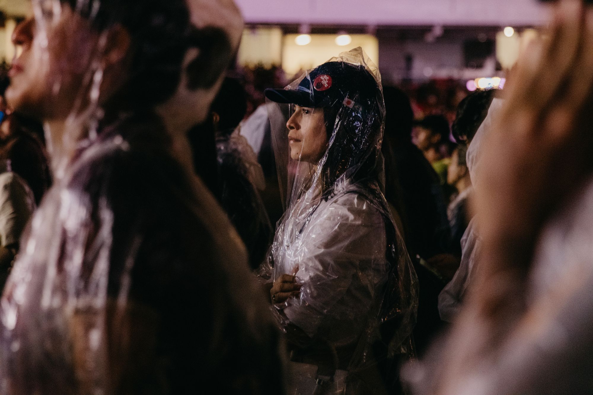 Público con impermeables y ponchos de plástico en un concierto al aire libre bajo la lluvia