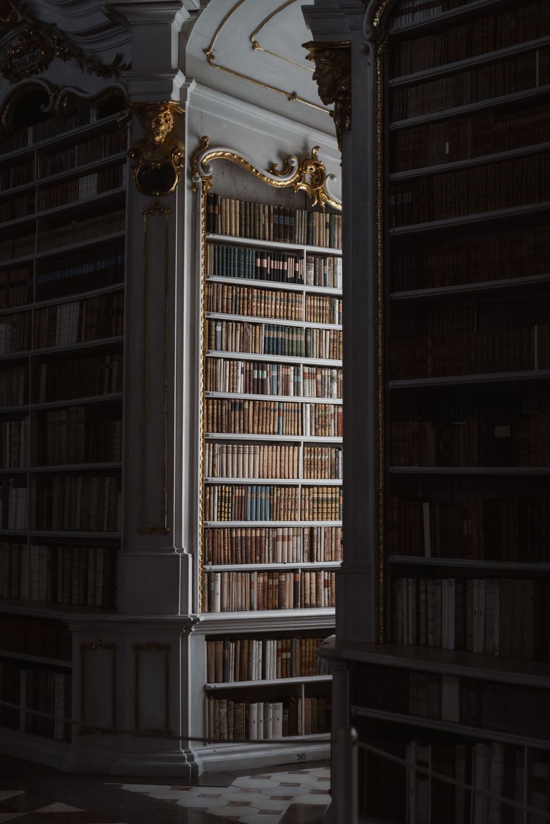 A beautifully lit view of an antique library featuring gold accents and rare books.