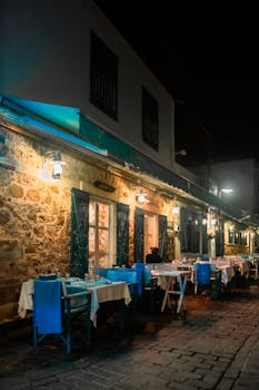 Cozy outdoor dining at a charming Mediterranean restaurant with vibrant blue chairs and a rustic stone wall.