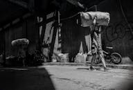 Urban Life: Man Carrying Bundle in Alley