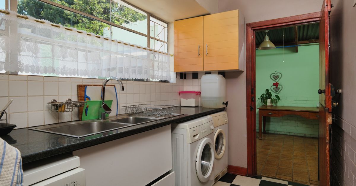 Contemporary kitchen featuring sink, washing machine, and garden view with natural light.