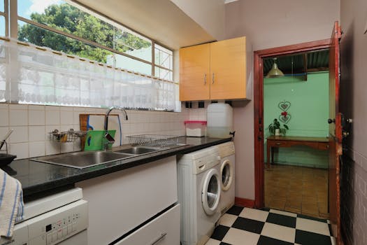 Contemporary kitchen featuring sink, washing machine, and garden view with natural light.