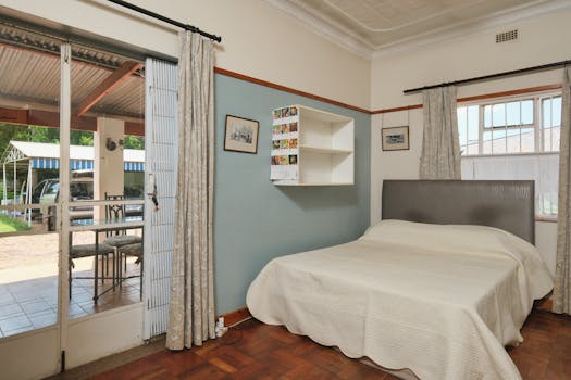 Inviting bedroom featuring blue accent wall and access to a covered outdoor patio area.