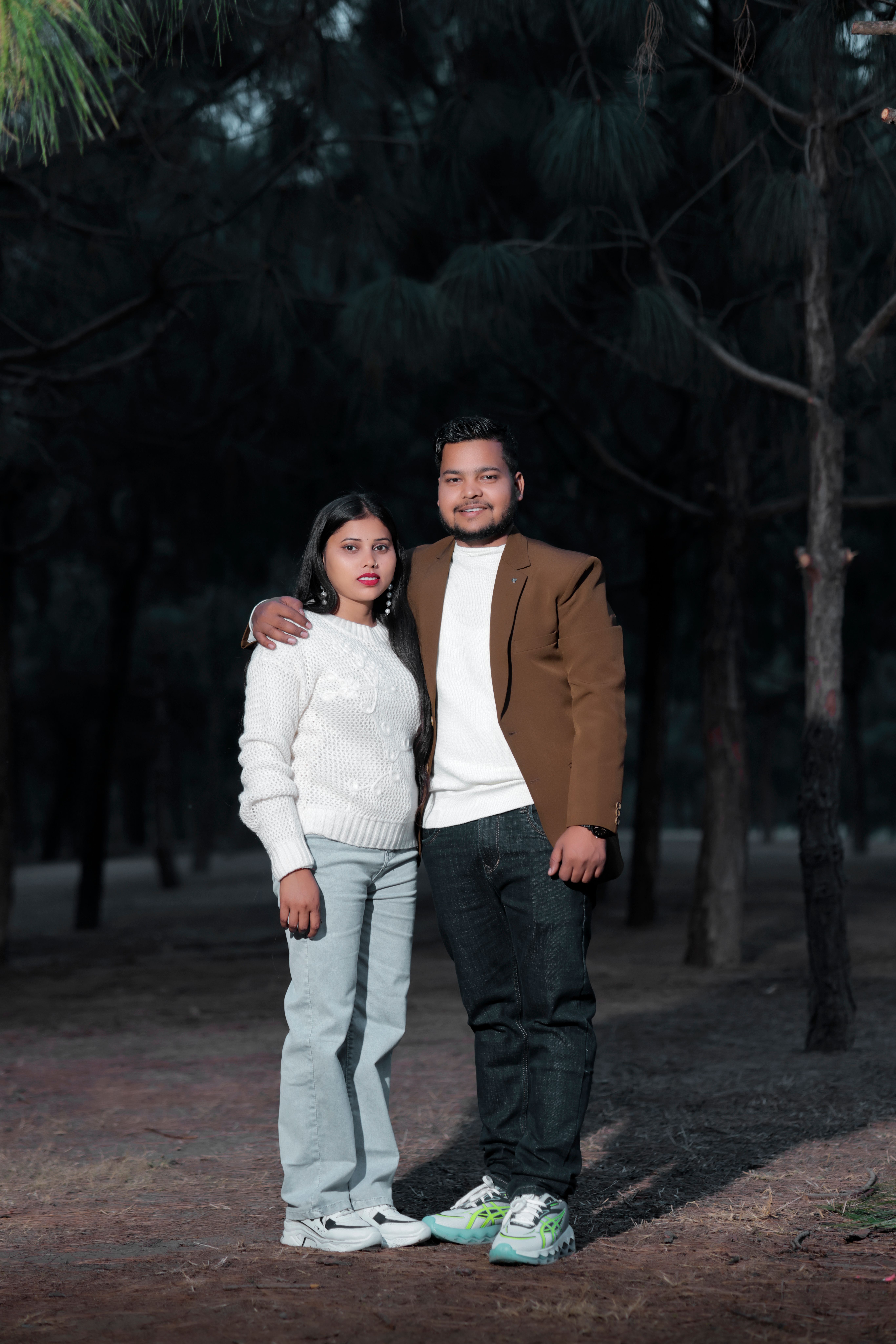 Couple standing together in a forest, showcasing a romantic and serene mood.