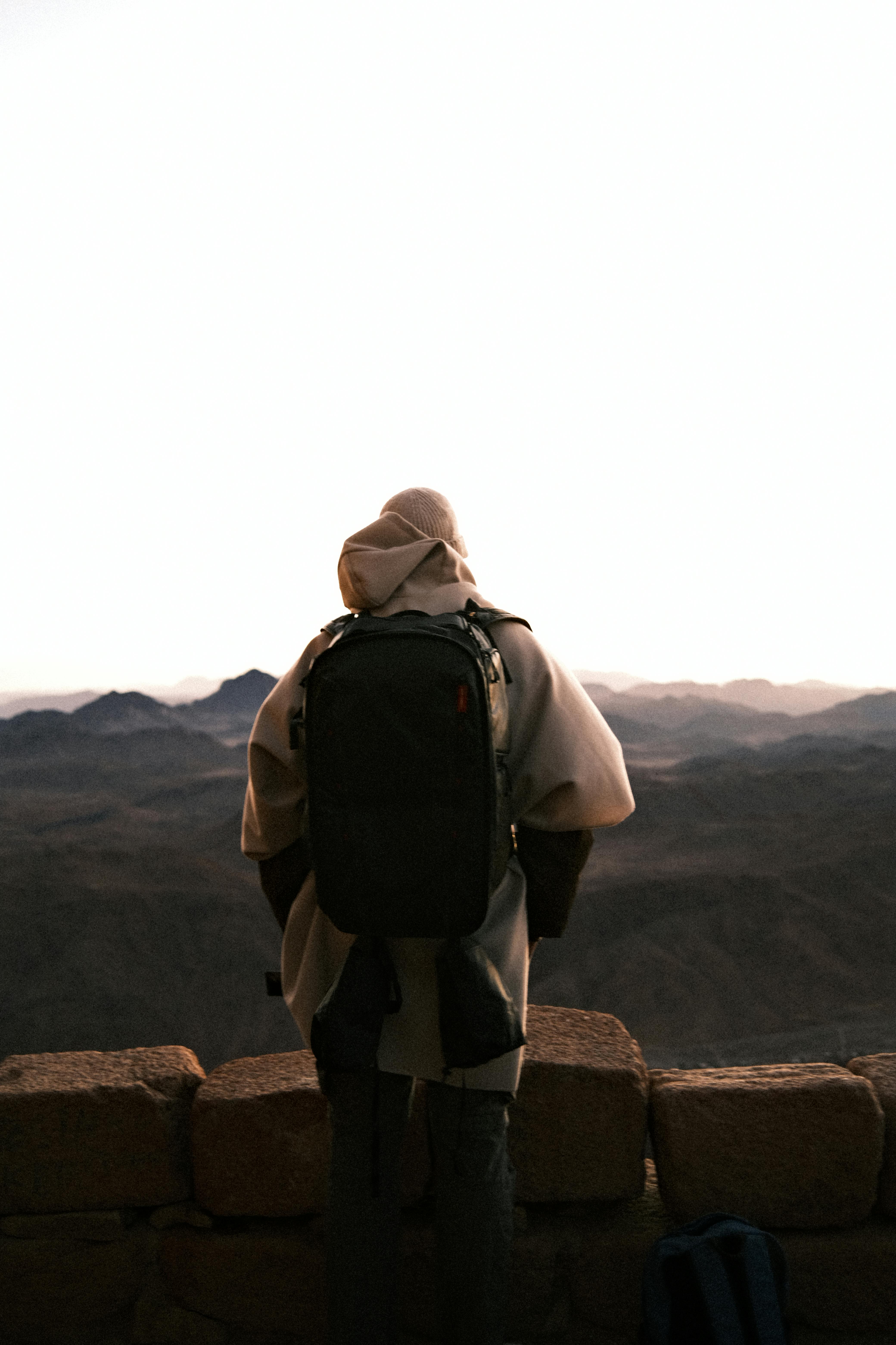 Gratis Un viaggiatore solitario con uno zaino in spalla osserva l'alba sulle montagne di Dschanub Sina, in Egitto. Foto a disposizione