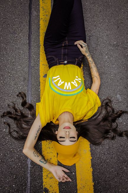A woman in vibrant yellow clothing lies down on a street, embracing relaxation and style.