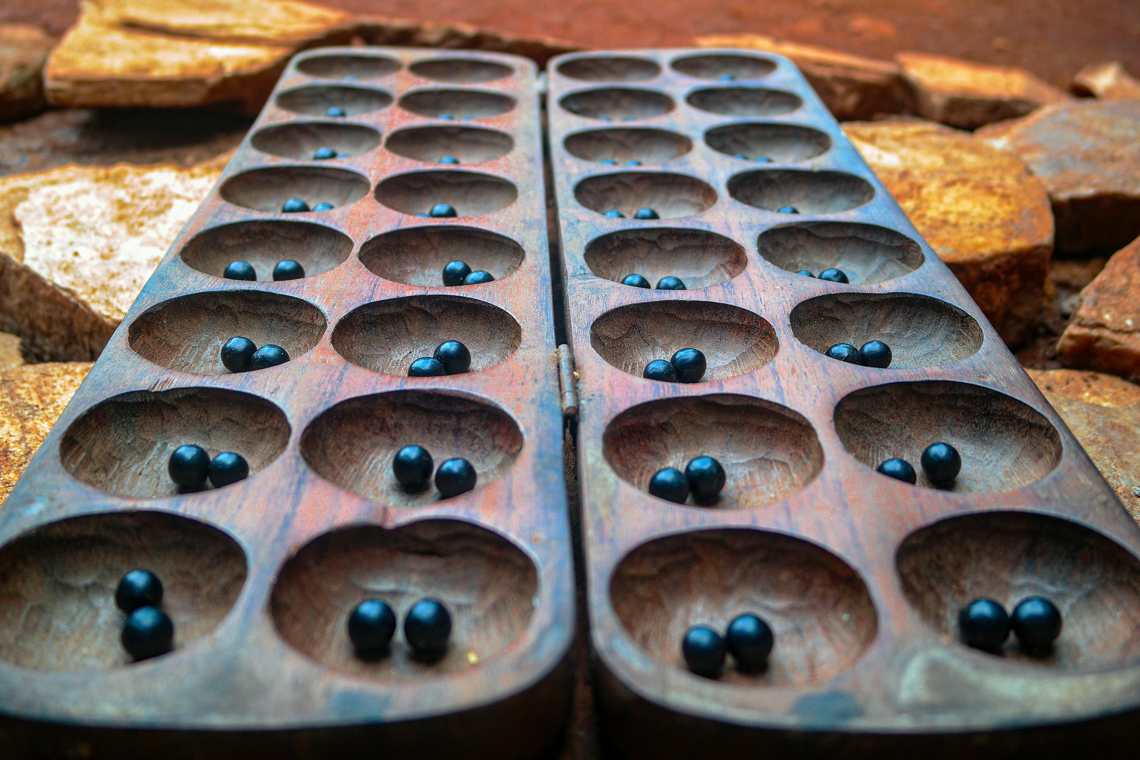 Close-up of a wooden Mancala board with stones outdoors in Uganda.