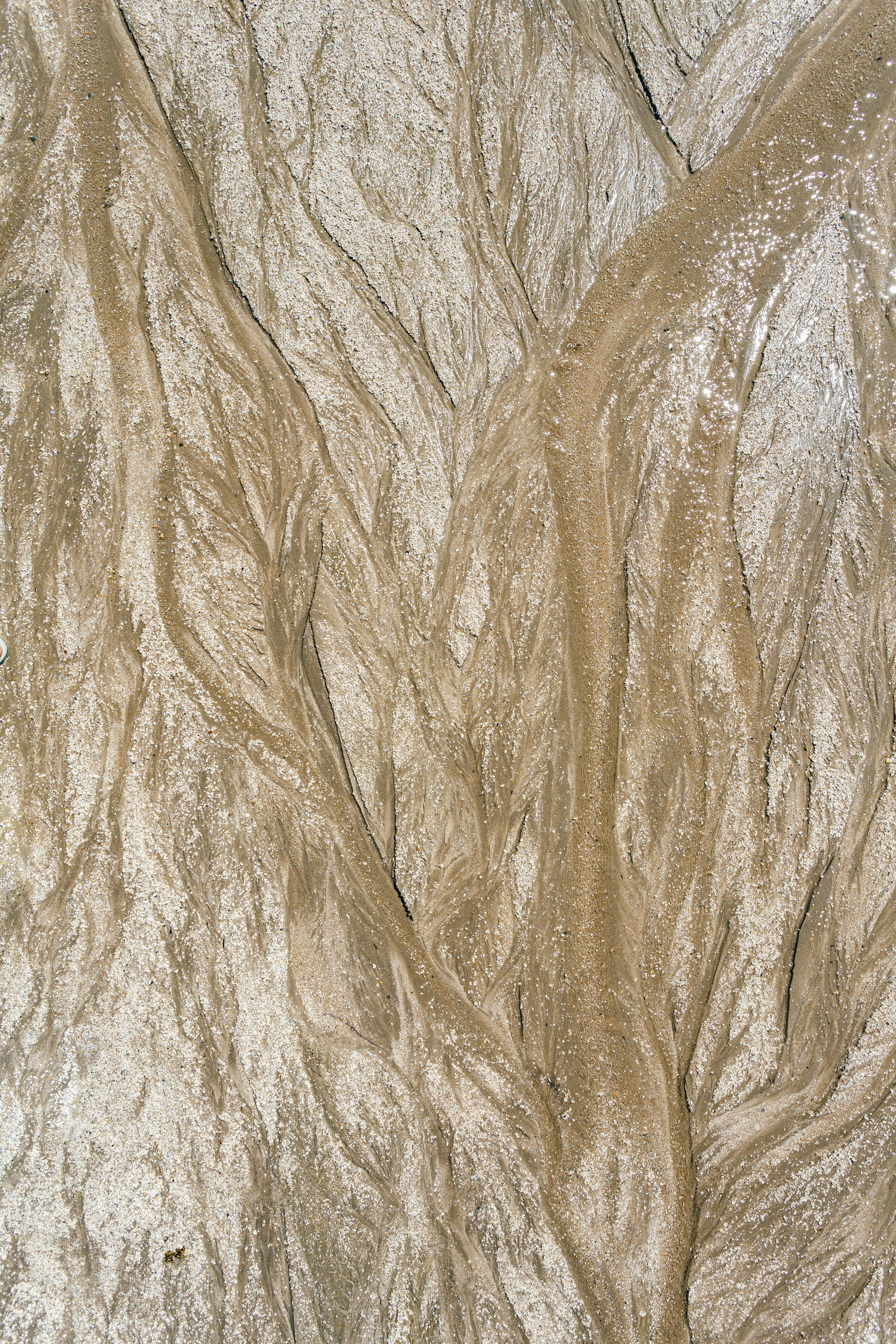 Zadarmo Detailný záber prírodných piesočných útvarov na pláži, ktoré ukazujú jedinečné textúry a vzory. Fotka z fotobanky