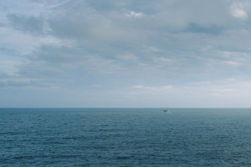 Free Peaceful ocean scene with a boat under a blue sky in Mar del Plata, Argentina. Stock Photo