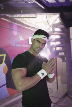 Athletic male posing indoors with urban graffiti backdrop, showing strength.
