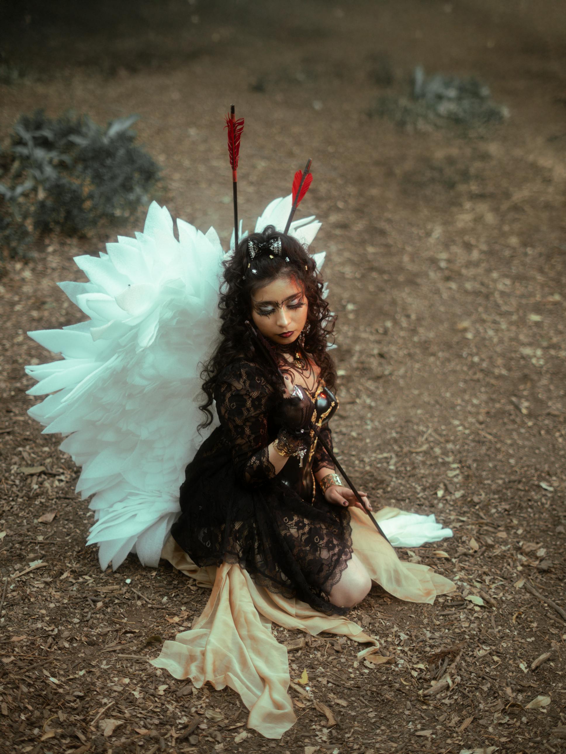 Gratuit Une femme vêtue comme un ange fantastique avec des ailes, agenouillée dans un décor forestier. Photos