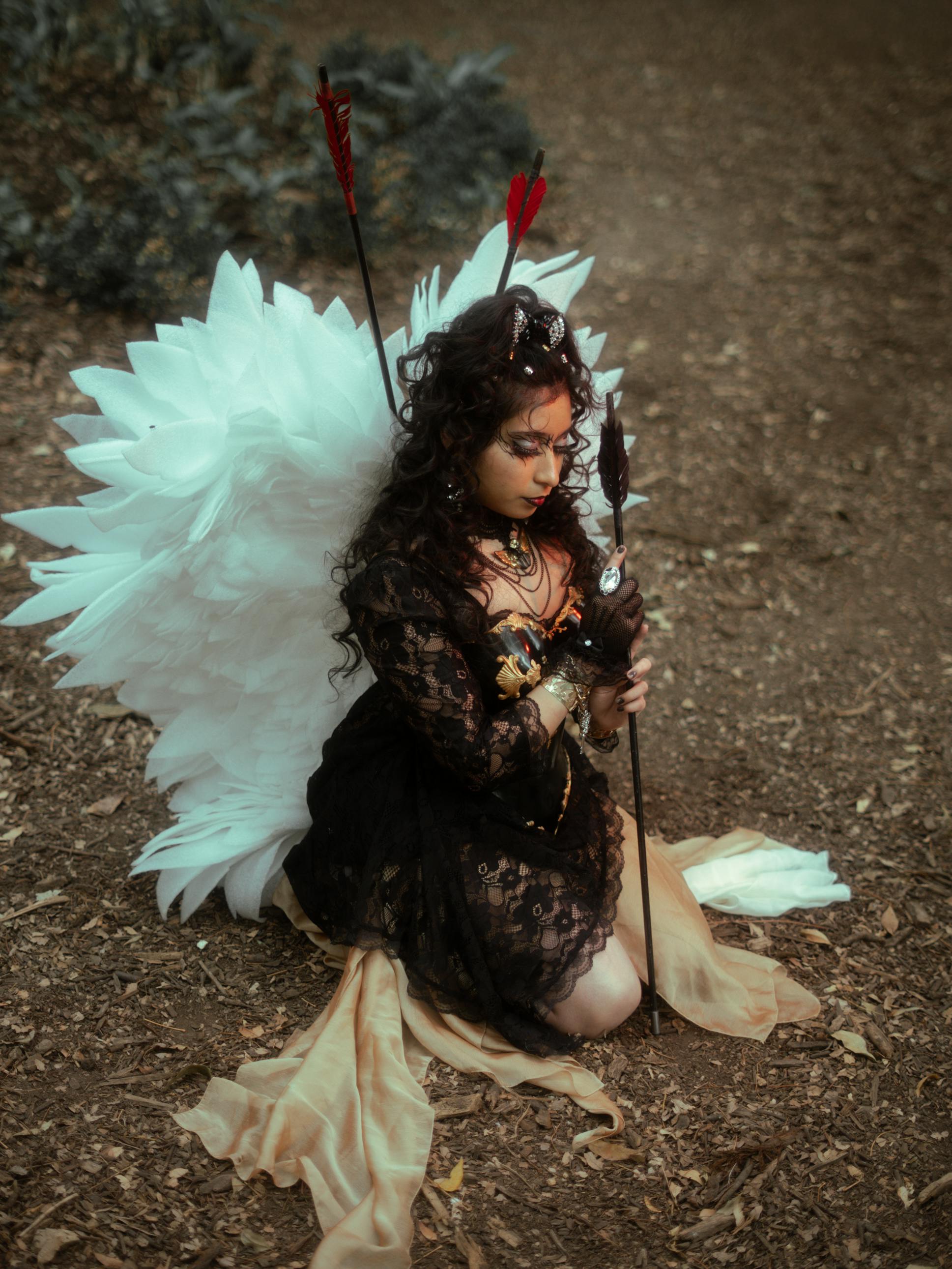 Gratis Elegante modelo con temática de ángel arrodillada en un bosque, con alas blancas. Foto de stock