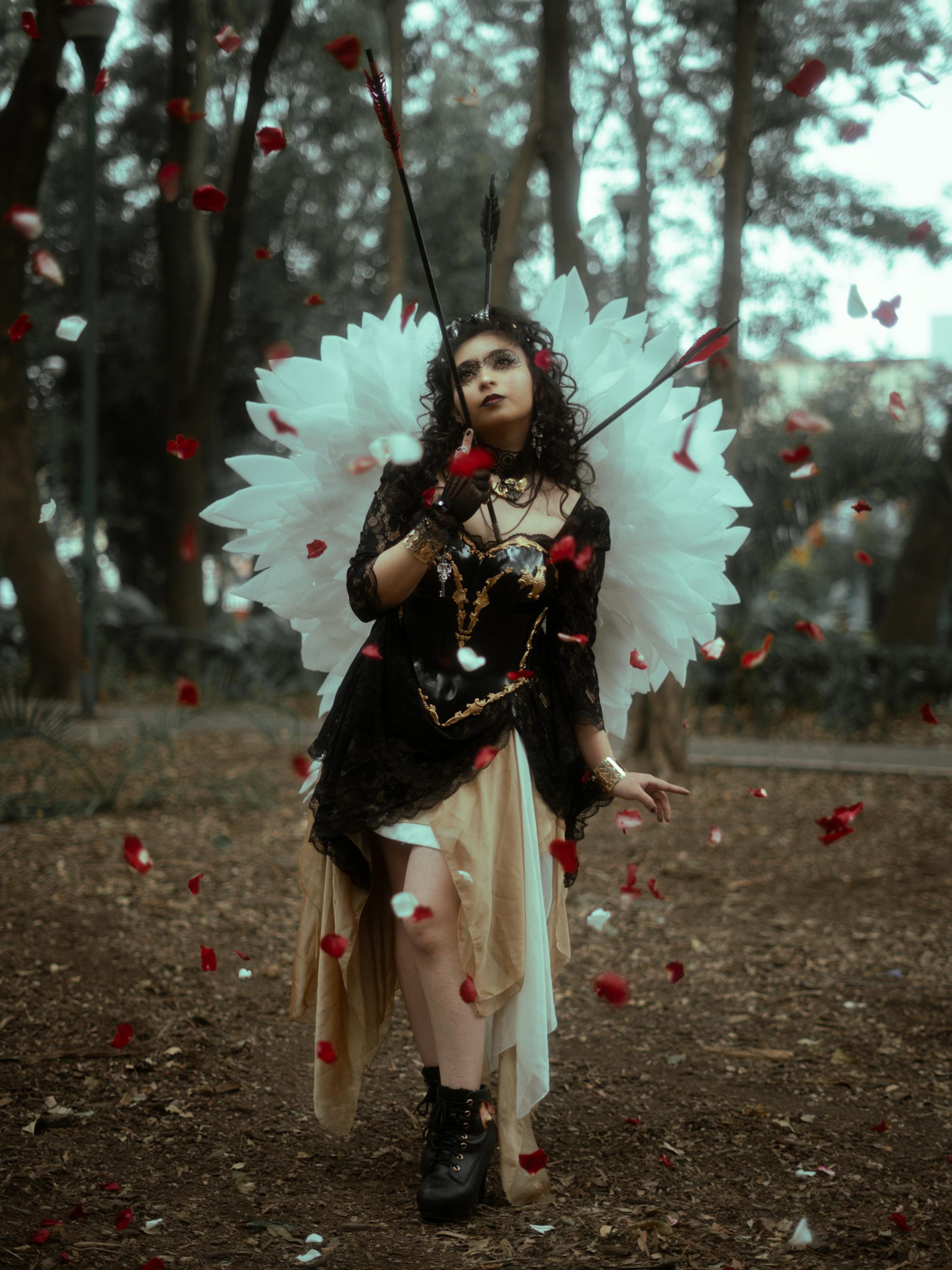 Free Captivating photo of a woman in angel costume amidst falling petals in a forest. Stock Photo