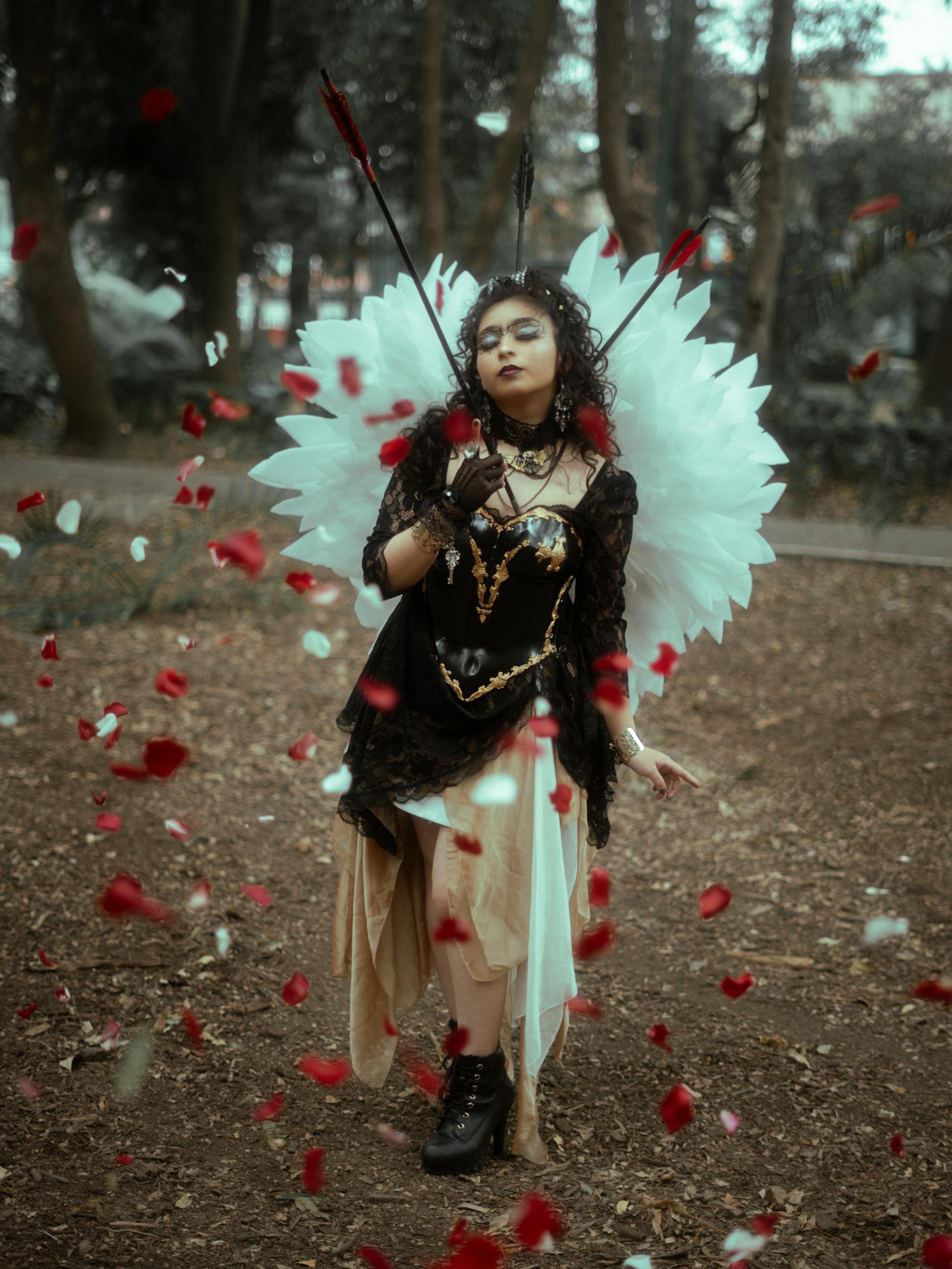 Free A captivating dark fairy cosplay with wings and petals in a mystical forest setting. Stock Photo