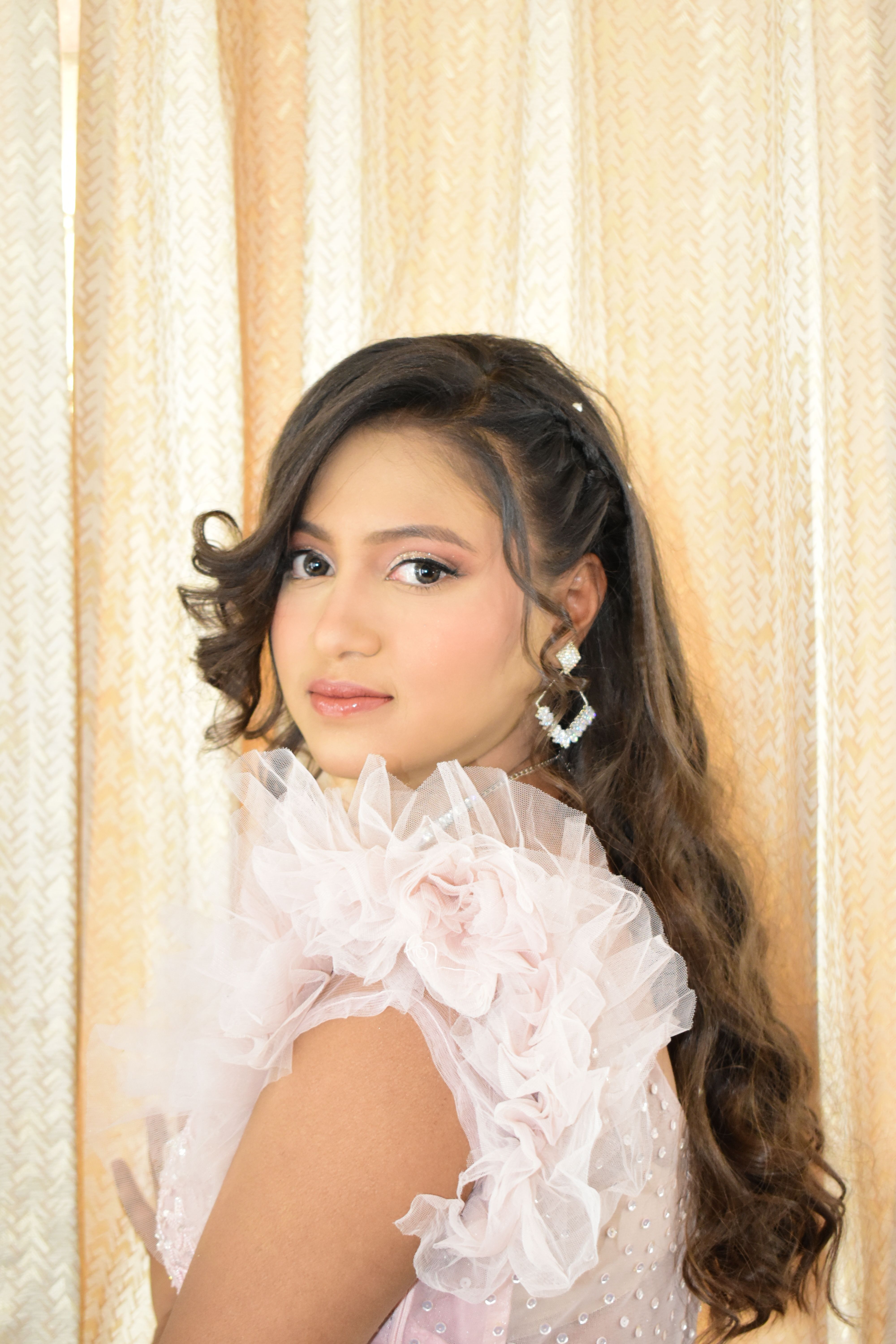 Chic portrait of a young woman with long hair, wearing a pink floral dress.