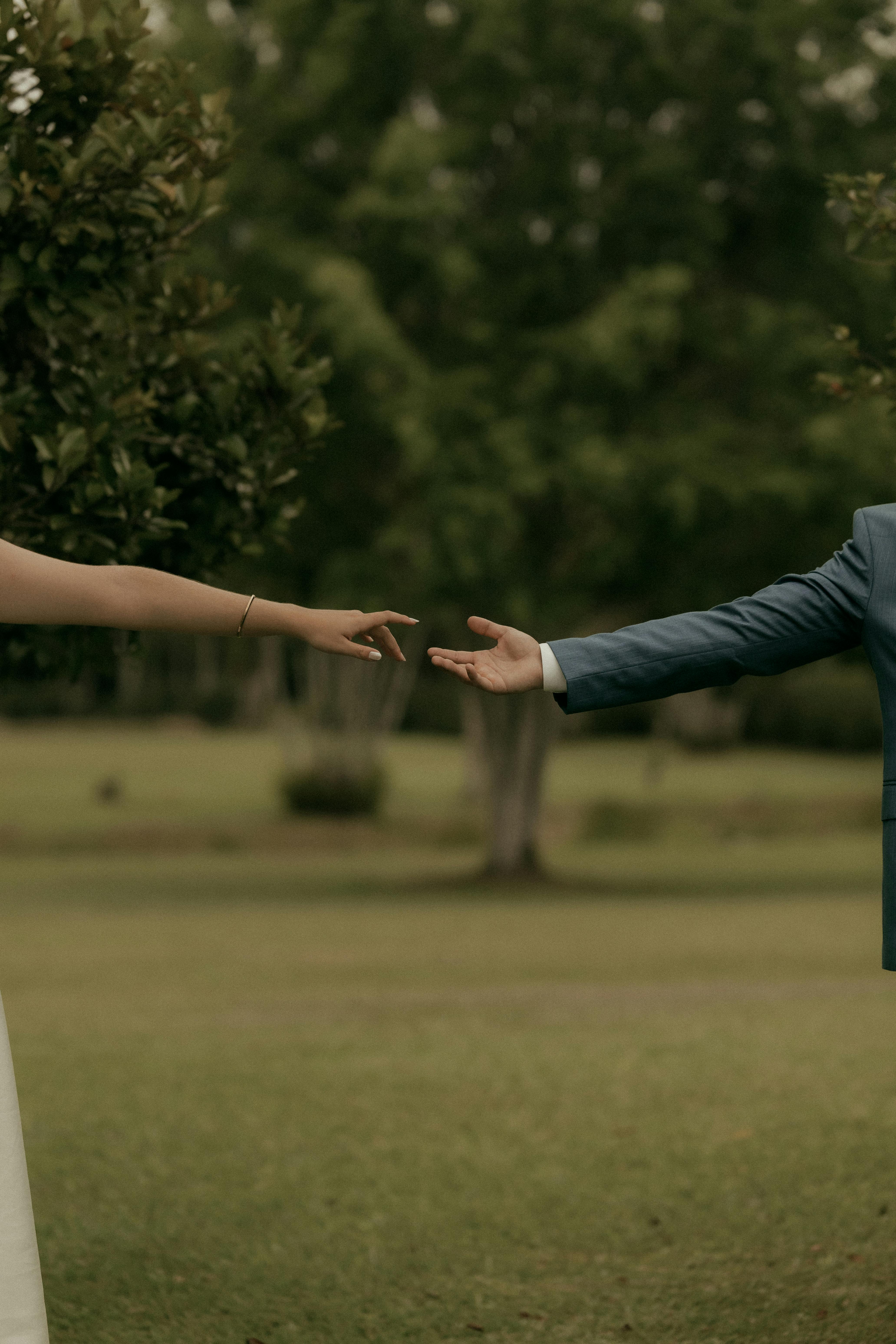 Безкоштовне Зворушливий момент рук, що простягаються одна до одної на романтичному весіллі просто неба. стокове фото