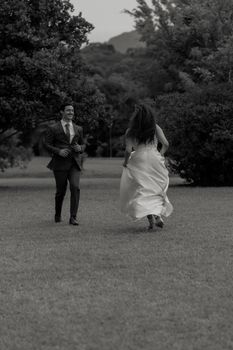 Romantic moment captured in a park with a couple joyfully running, in black and white.